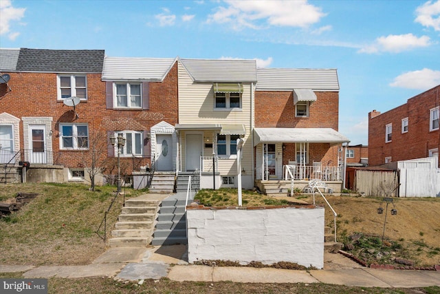 townhome / multi-family property with covered porch and brick siding