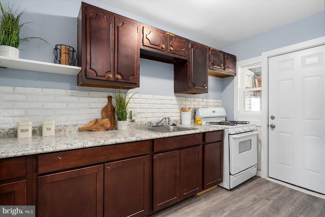 kitchen with wood finished floors, open shelves, a sink, white gas range, and backsplash