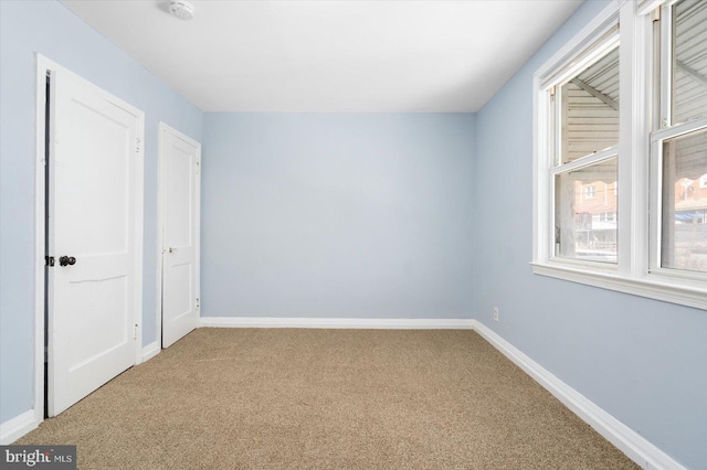 unfurnished room with baseboards and carpet