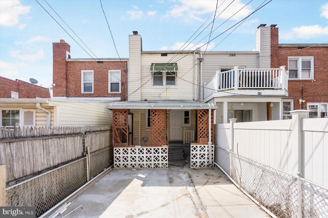 rear view of house featuring a fenced front yard, entry steps, and a balcony