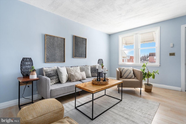 living area with wood finished floors, baseboards, and a textured ceiling