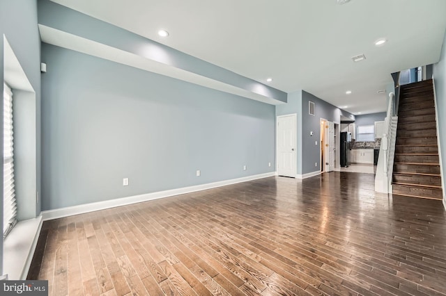 unfurnished living room with stairs, dark wood-type flooring, recessed lighting, and baseboards