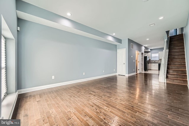 1712 N Washington St, Baltimore, MD 21213 - unfurnished living room with stairs, dark wood-type flooring, recessed lighting, and baseboards