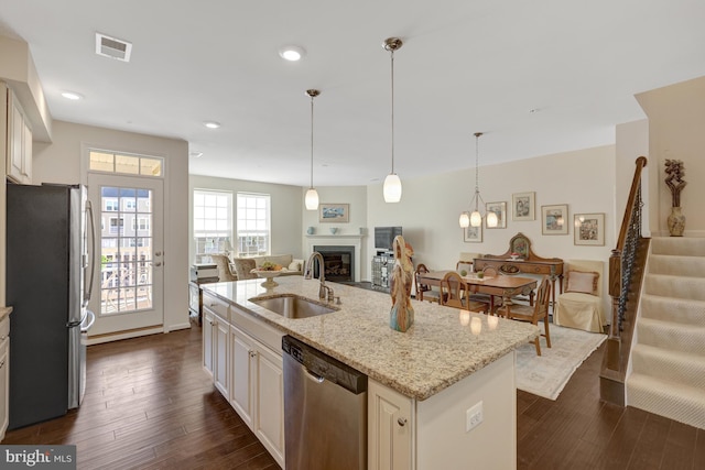 kitchen with a fireplace, a sink, dark wood-type flooring, appliances with stainless steel finishes, and open floor plan