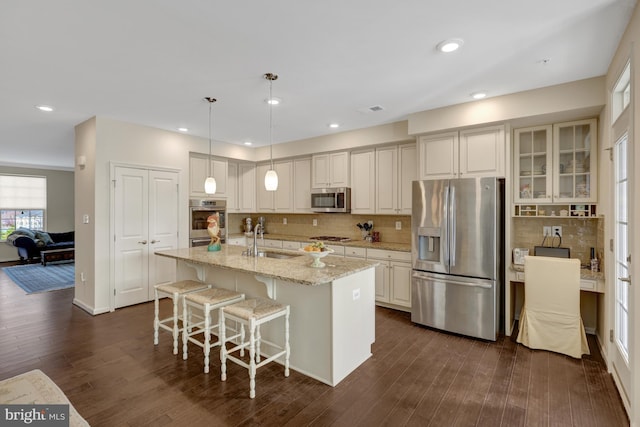 kitchen with light stone countertops, stainless steel appliances, dark wood-type flooring, and a sink