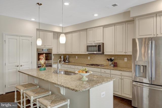 kitchen featuring visible vents, dark wood-style flooring, a sink, stainless steel appliances, and backsplash