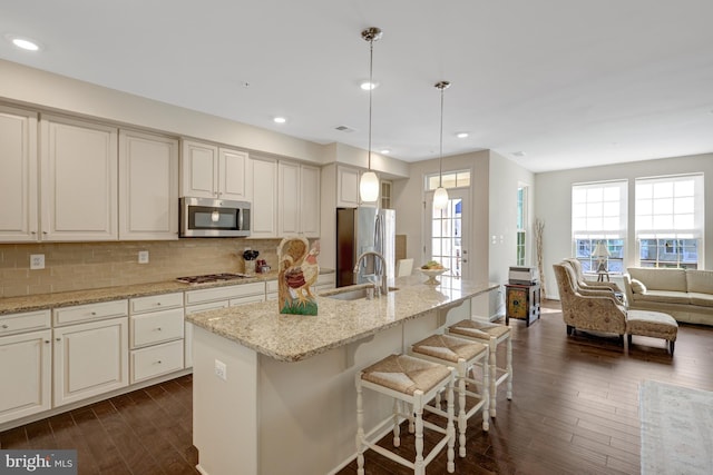 kitchen with a sink, stainless steel appliances, tasteful backsplash, and dark wood-style flooring