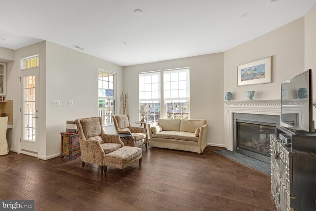 living room featuring visible vents, a fireplace with flush hearth, dark wood-type flooring, and baseboards