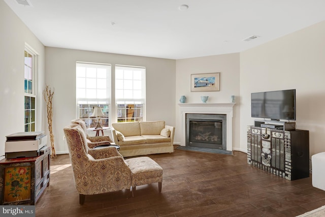 living room featuring a glass covered fireplace, visible vents, and wood finished floors