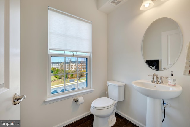 half bath featuring wood finished floors, toilet, baseboards, and visible vents