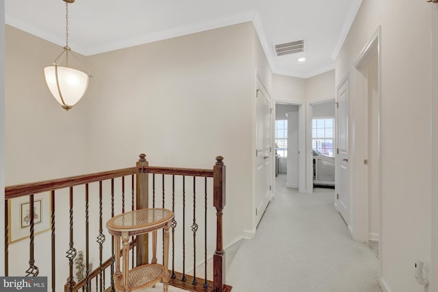 corridor with visible vents, baseboards, an upstairs landing, crown molding, and light colored carpet