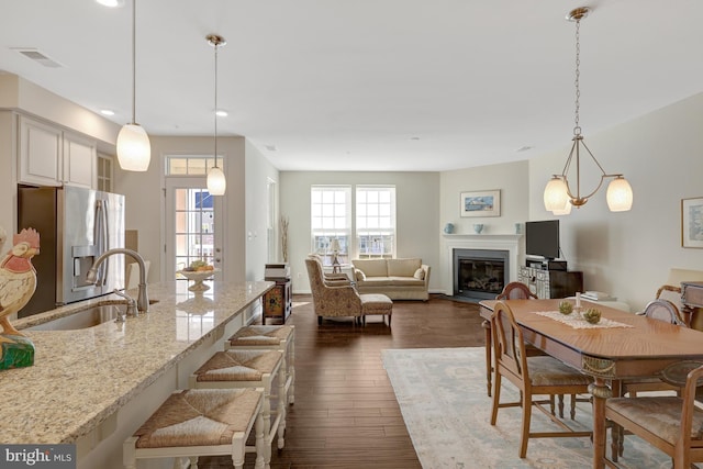 dining area with dark wood finished floors, a fireplace with flush hearth, recessed lighting, and visible vents