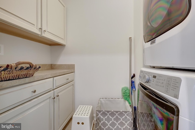 laundry room with cabinet space and stacked washing maching and dryer