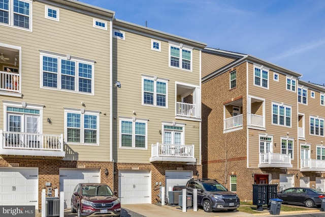 rear view of property with an attached garage, central AC unit, and brick siding