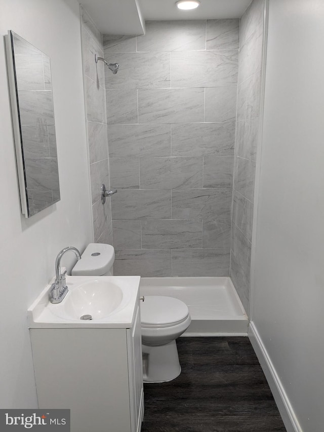 full bath with baseboards, toilet, a stall shower, wood finished floors, and vanity