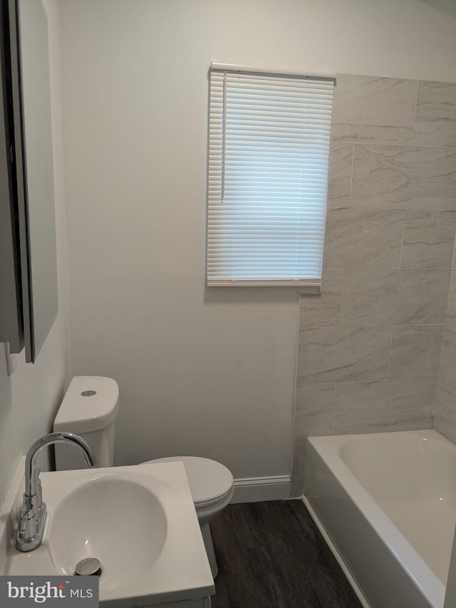 bathroom with a sink, baseboards, toilet, and wood finished floors