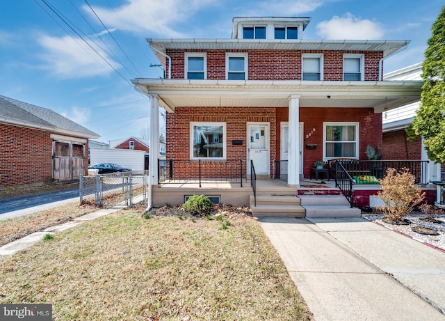 traditional style home featuring brick siding, covered porch, and a gate