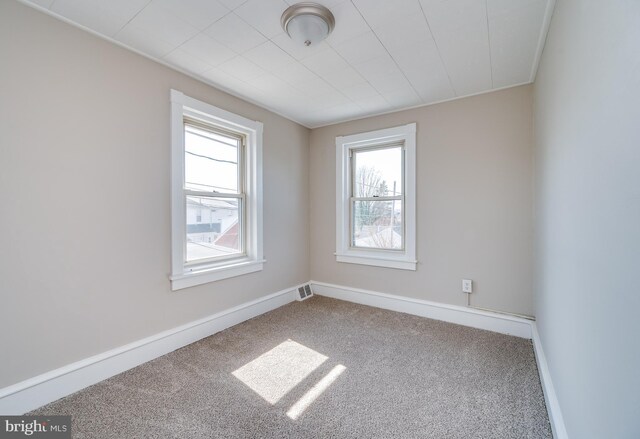 carpeted empty room featuring visible vents and baseboards