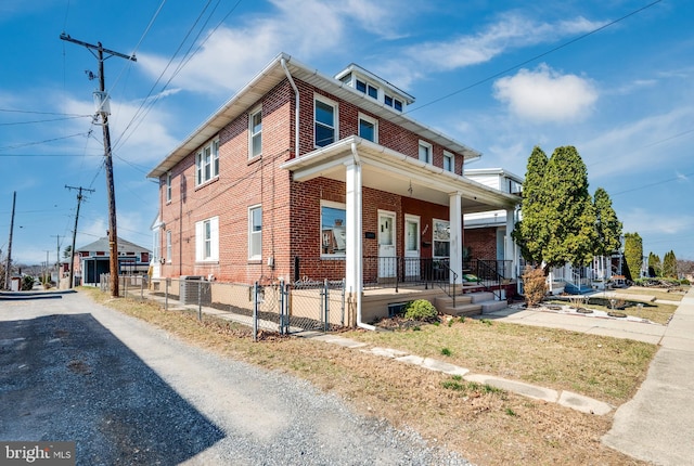 view of side of property featuring a gate, cooling unit, fence, a porch, and brick siding