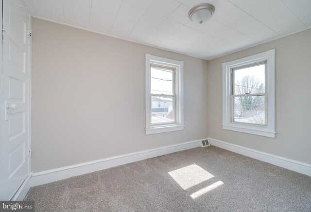 unfurnished room with visible vents, baseboards, and carpet floors