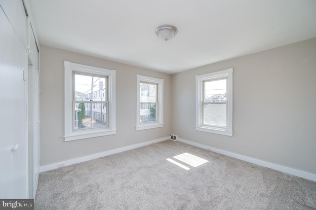 carpeted spare room featuring visible vents and baseboards