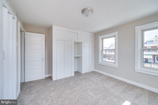 unfurnished bedroom featuring a closet, baseboards, and light colored carpet