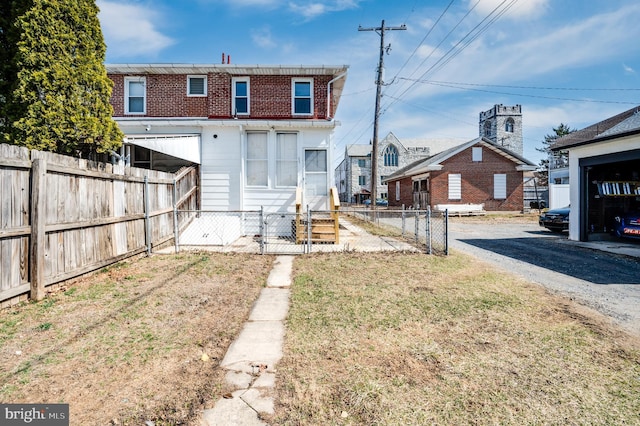 back of property featuring entry steps, aphalt driveway, fence private yard, and brick siding