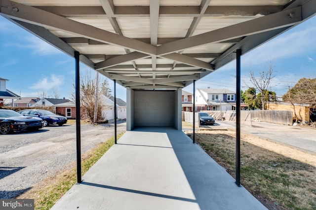 view of patio featuring a detached garage, fence, and a residential view