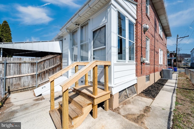 view of side of property with brick siding, cooling unit, and fence