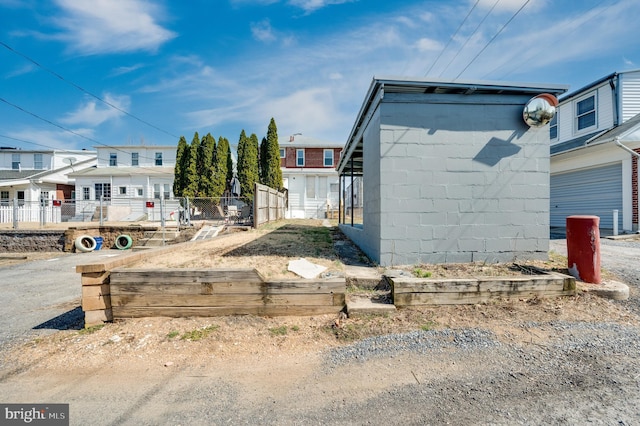 view of side of home featuring a garage, concrete block siding, and fence