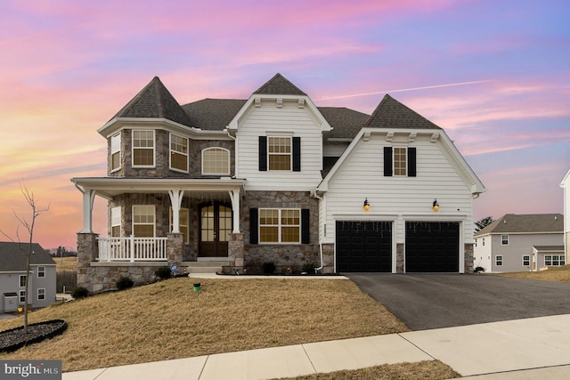 view of front of home with driveway, stone siding, roof with shingles, covered porch, and a garage