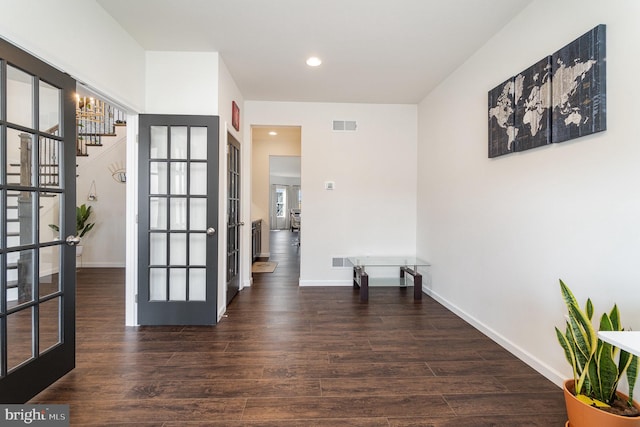 hall with wood finished floors, french doors, visible vents, and baseboards