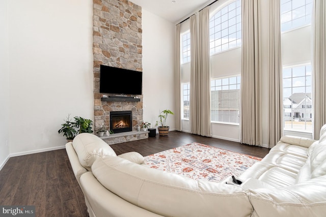 living room featuring baseboards, a high ceiling, wood finished floors, and a fireplace