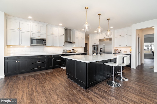 kitchen featuring wall chimney range hood, appliances with stainless steel finishes, white cabinets, light countertops, and dark cabinets