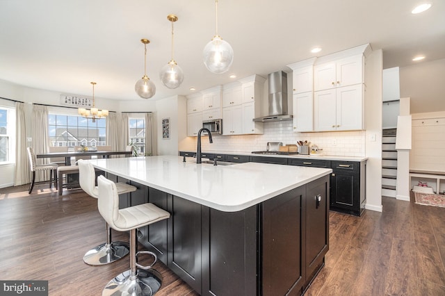 kitchen with backsplash, dark wood finished floors, appliances with stainless steel finishes, white cabinetry, and wall chimney exhaust hood