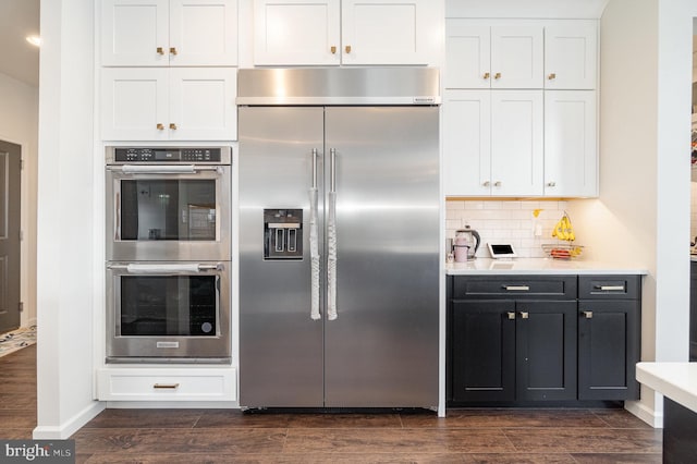 kitchen featuring dark wood finished floors, white cabinets, backsplash, and appliances with stainless steel finishes