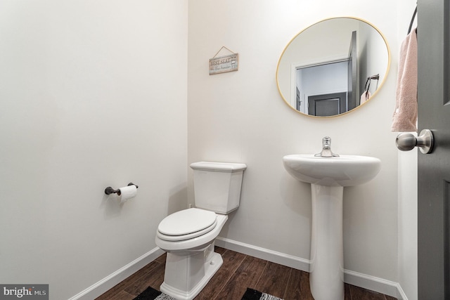 half bathroom with toilet, baseboards, and wood finished floors