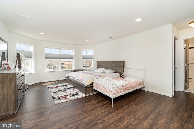 bedroom with baseboards, multiple windows, and dark wood-type flooring