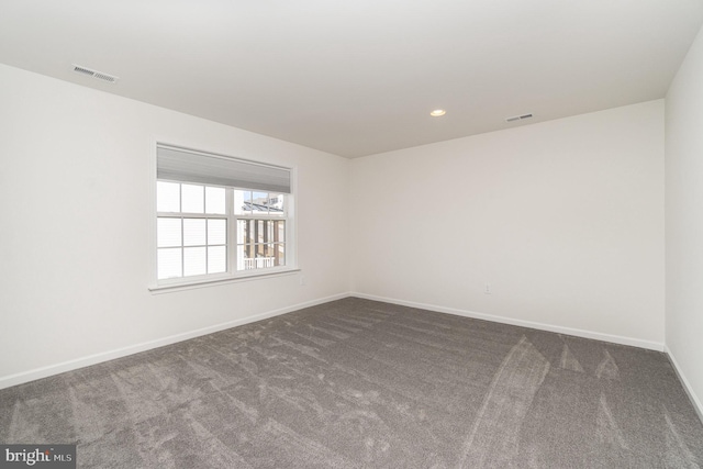 empty room with visible vents, baseboards, and dark carpet