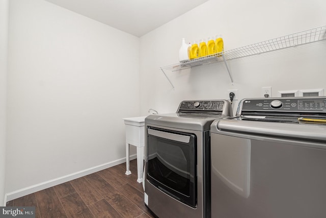 laundry room with dark wood finished floors, laundry area, washing machine and dryer, and baseboards