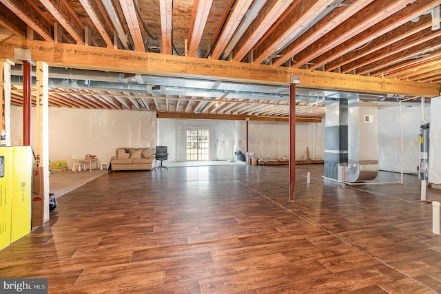 below grade area with heating unit, wood finished floors, and water heater