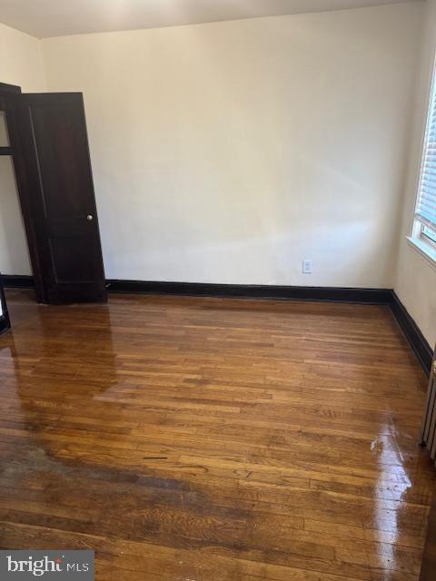 spare room with dark wood finished floors and baseboards