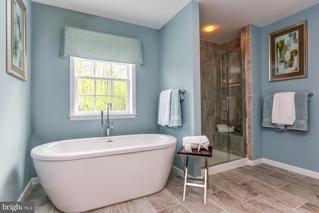 bathroom featuring baseboards, a soaking tub, and a shower stall