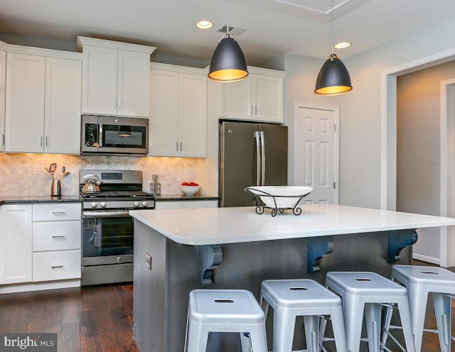 kitchen with visible vents, dark wood-style floors, white cabinetry, appliances with stainless steel finishes, and decorative backsplash