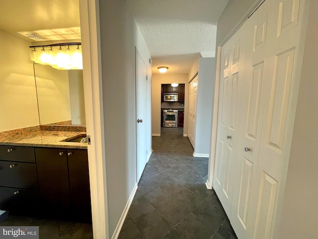 hall with baseboards and a textured ceiling