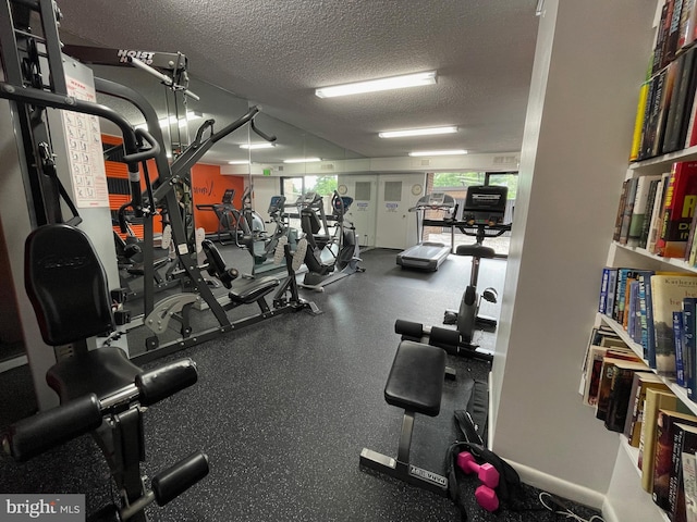 exercise room with baseboards and a textured ceiling