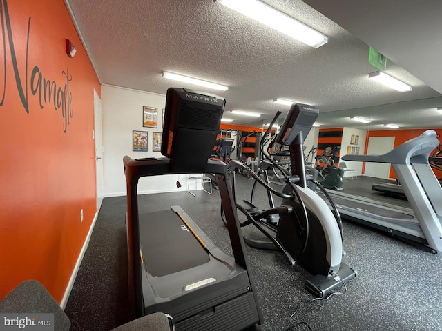 gym with a textured ceiling and baseboards