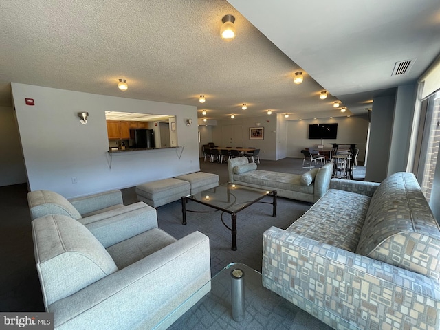 carpeted living room with visible vents and a textured ceiling