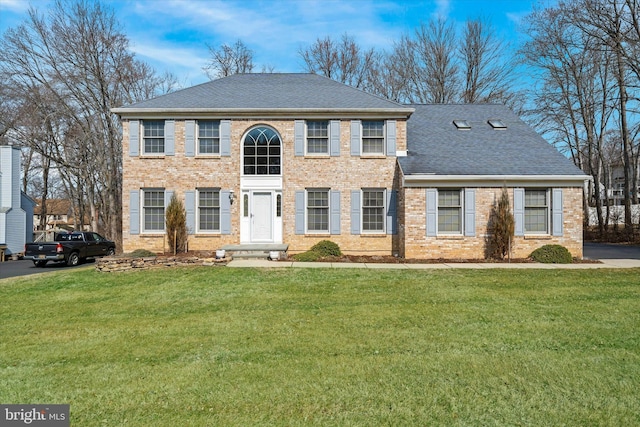 view of front facade with brick siding, a front lawn, and a shingled roof