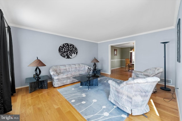 living room featuring visible vents, baseboards, wood finished floors, and crown molding